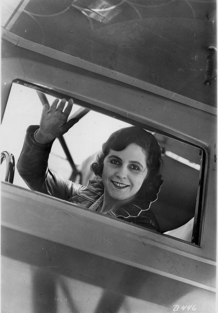 Die Aufnahme zeigt Lady Hay, die im Cockpit ihres Flugzeuges sitzt und aus dem Fenster winkt. 