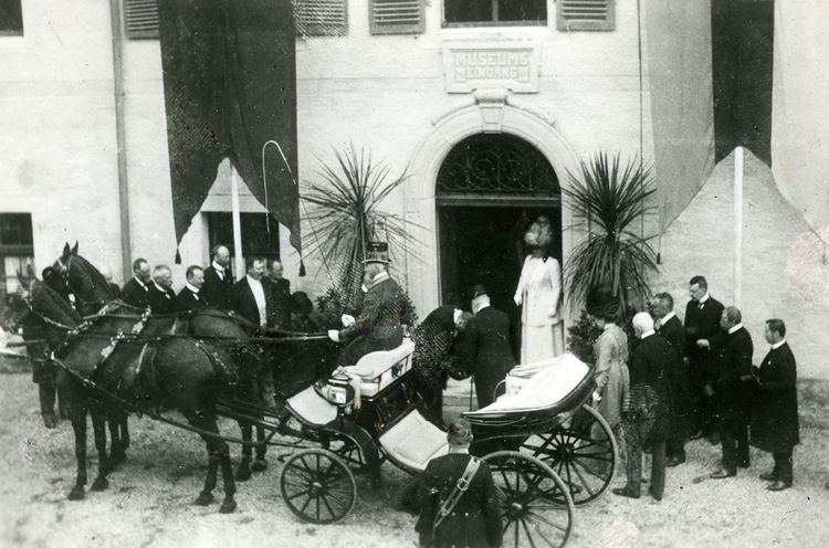 Eröffnung des Museums im Kreuzlinger Hof. Im Hintergrund der Museumseingang. Einige Menschen begrüßen das württembergische Königspaar, das in einer Kutsche angekommen ist.