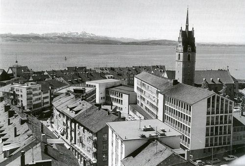 Die historische Aufnahme zeigt die Stadt Friedrichshafen wie sie früher aussah aus der Vogelperspektive. Neben dem Rathaus sind viele weitere Gebäude abgebildet.